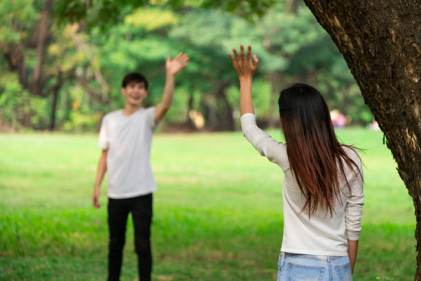 Young-people-man-and-woman-greeting-or-saying-goodbye-by-waving-hands-in-the-park